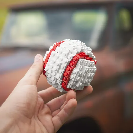 A baseball built from bricks, held in a hand